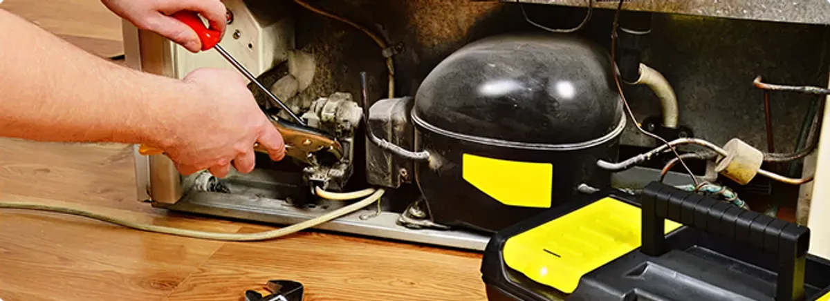 Refrigerator repair technician fixing the compressor and wiring in Tolleson, AZ