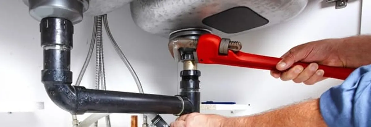 Garbage disposal repair technician tightening the sink drain and disposal connection in Glendale, AZ
