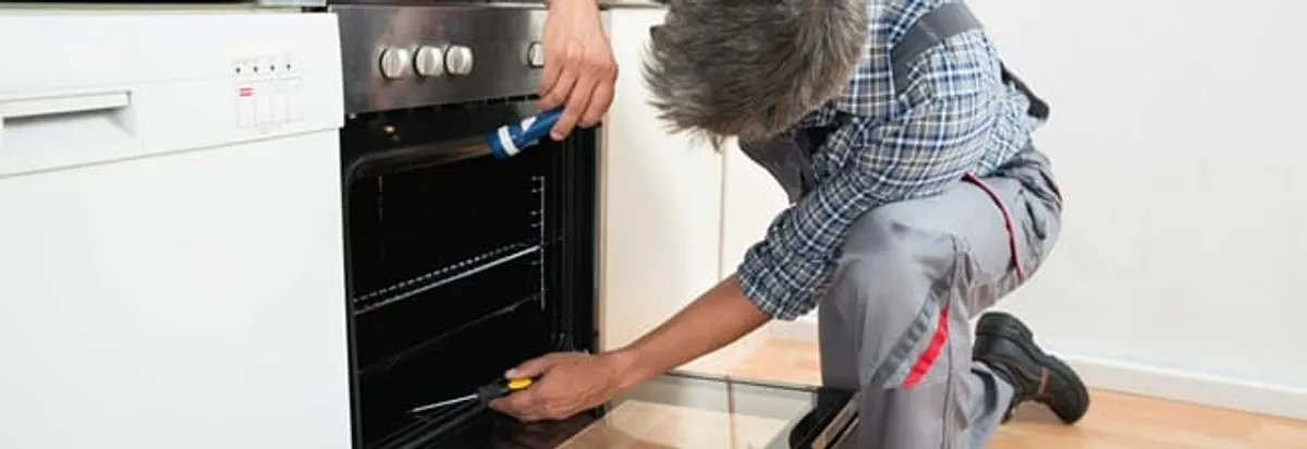 Oven repair technician inspecting and servicing an electric oven in Glendale, AZ